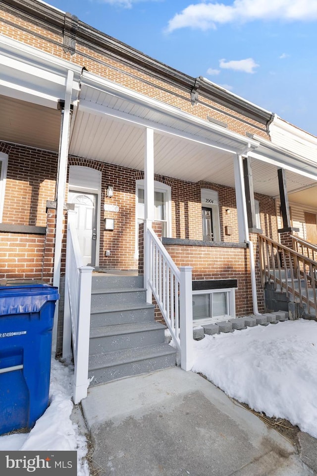 snow covered property entrance with a porch