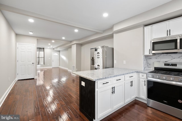 kitchen with light stone countertops, kitchen peninsula, white cabinetry, and stainless steel appliances