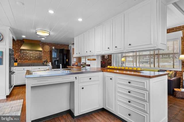 kitchen with custom range hood, sink, white cabinets, and kitchen peninsula