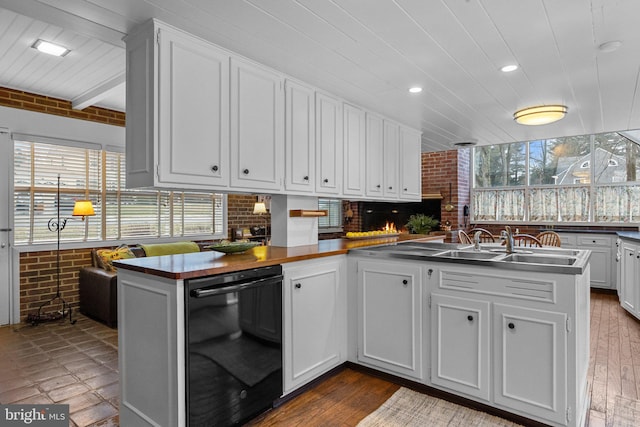 kitchen with brick wall, dishwasher, white cabinets, hardwood / wood-style flooring, and kitchen peninsula