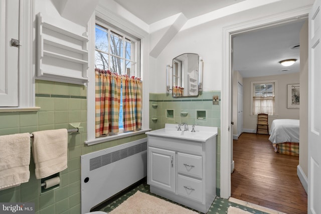 bathroom featuring tile walls, radiator, vanity, and a healthy amount of sunlight