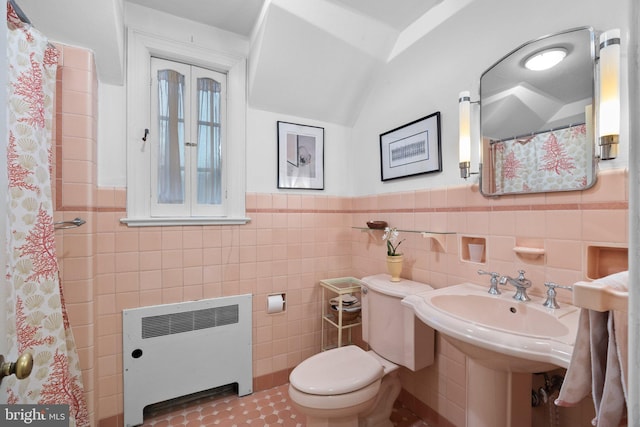 bathroom with toilet, radiator, and tile walls