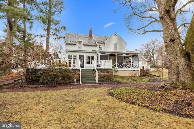 rear view of property with a wooden deck, a yard, and a sunroom