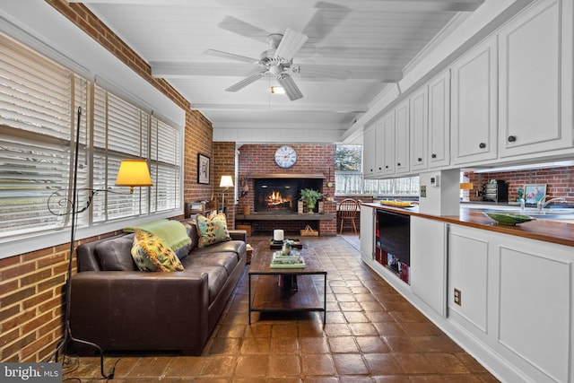 living room featuring brick wall, plenty of natural light, ceiling fan, and a brick fireplace