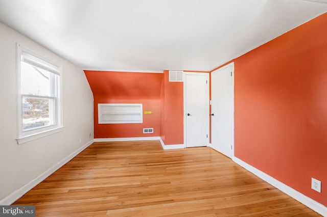 unfurnished room with light wood-type flooring and lofted ceiling