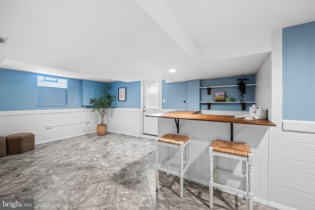 kitchen featuring a kitchen bar, blue cabinets, kitchen peninsula, and wood counters