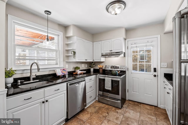 kitchen with white cabinets, appliances with stainless steel finishes, dark stone countertops, sink, and hanging light fixtures