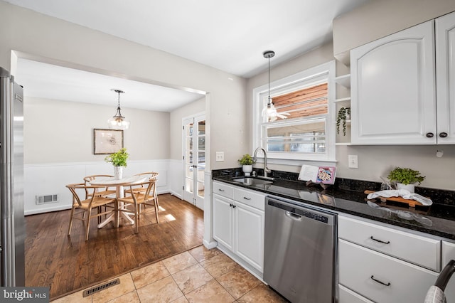 kitchen featuring stainless steel appliances, light tile patterned flooring, hanging light fixtures, white cabinets, and sink