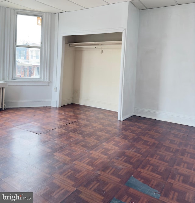 unfurnished bedroom with dark parquet floors and a closet