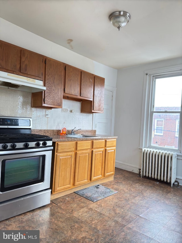 kitchen featuring stainless steel gas stove, tasteful backsplash, radiator, and sink