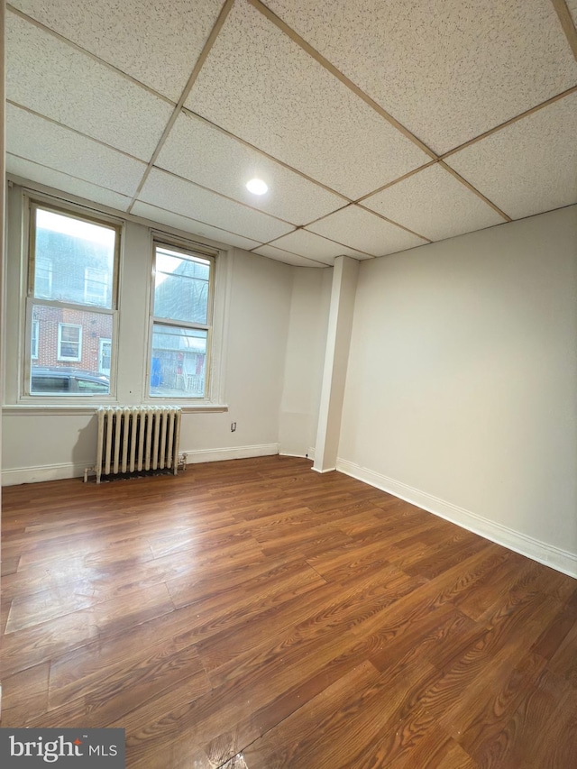 spare room with hardwood / wood-style floors, a paneled ceiling, and radiator