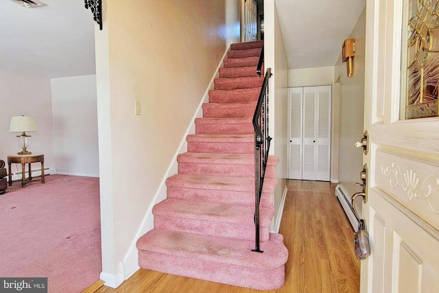 stairway featuring wood-type flooring and a baseboard heating unit