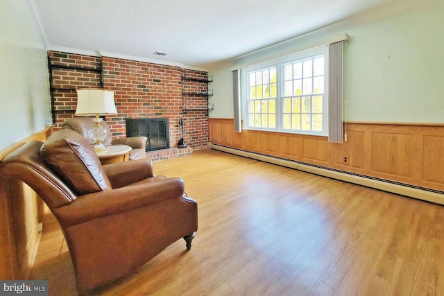 living room featuring light hardwood / wood-style floors, crown molding, a fireplace, and a baseboard radiator