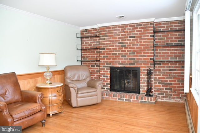 sitting room with a fireplace, light hardwood / wood-style flooring, baseboard heating, and ornamental molding