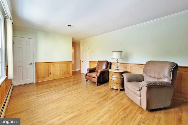 living area with light wood-type flooring, crown molding, and a baseboard radiator