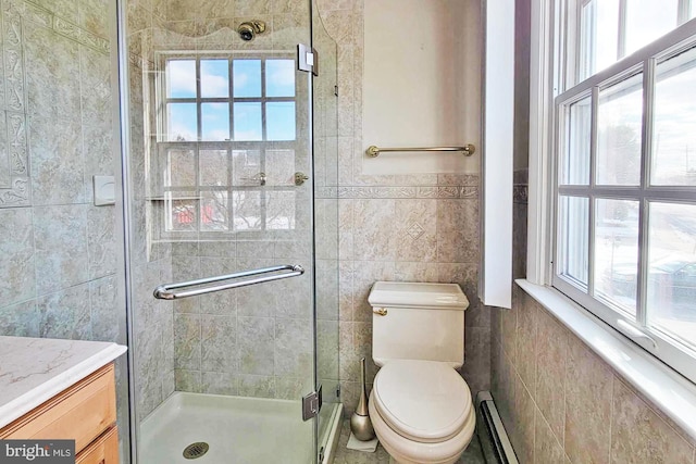 bathroom featuring a shower with door, toilet, tile walls, and a healthy amount of sunlight