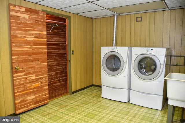 laundry area featuring washing machine and dryer, sink, and wooden walls