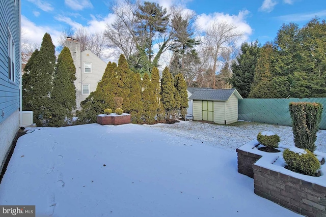 snowy yard featuring a storage shed