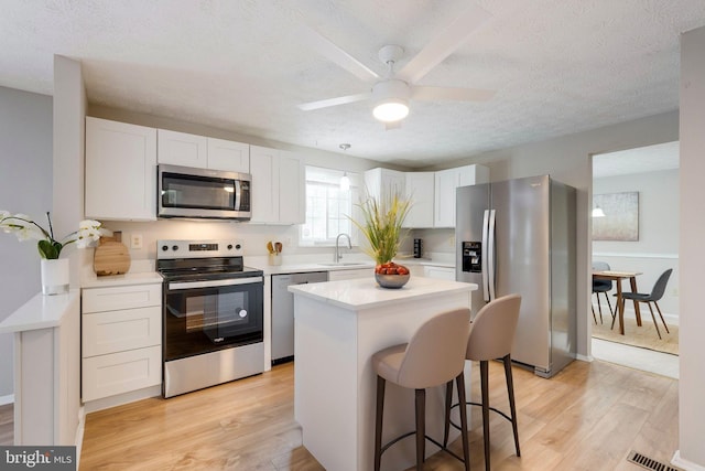 kitchen featuring appliances with stainless steel finishes, sink, a kitchen island, and white cabinets