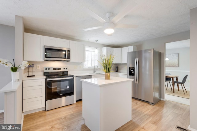 kitchen featuring sink, a center island, ceiling fan, stainless steel appliances, and white cabinets