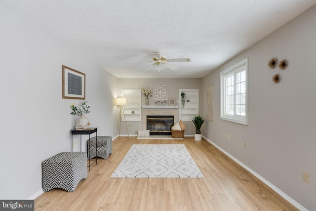 living room featuring a textured ceiling, light hardwood / wood-style flooring, and ceiling fan