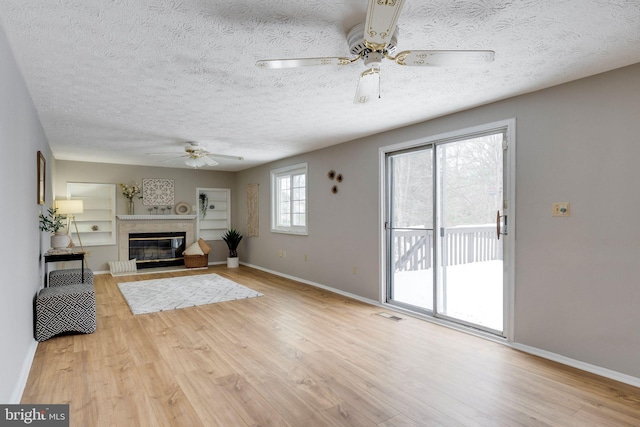 unfurnished living room with a textured ceiling, light hardwood / wood-style floors, and ceiling fan