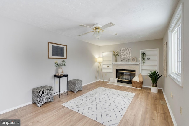 living area featuring wood-type flooring, a premium fireplace, built in features, and a textured ceiling