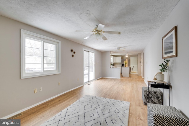 living room with ceiling fan, light hardwood / wood-style floors, and a textured ceiling