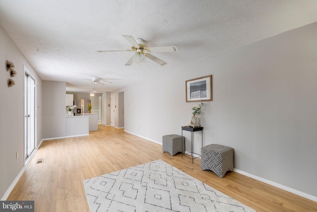 interior space featuring ceiling fan, a textured ceiling, and light wood-type flooring