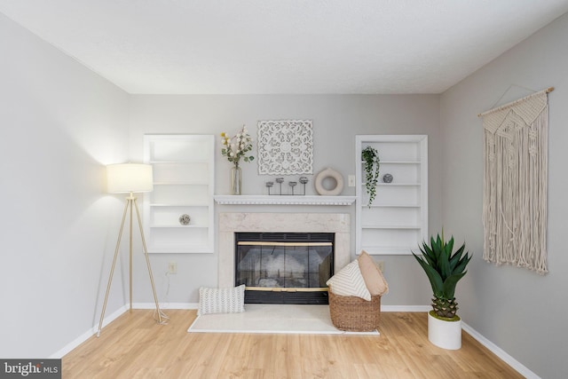 living room featuring a premium fireplace, hardwood / wood-style floors, and built in shelves