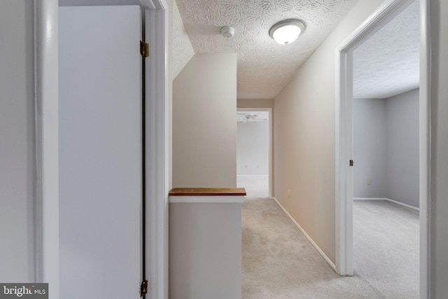 hall with light carpet and a textured ceiling