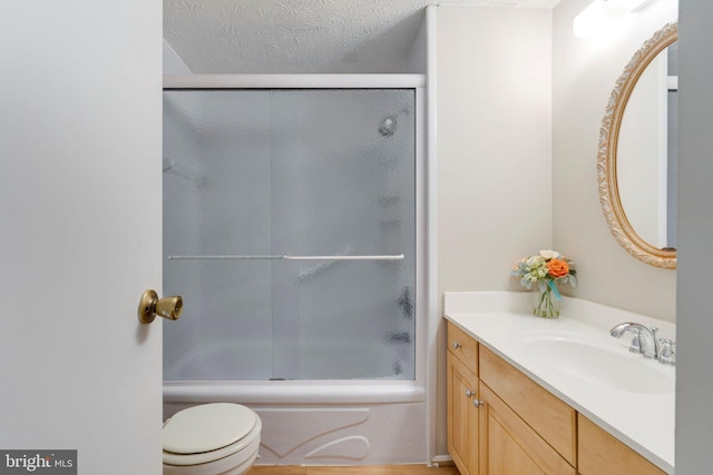 full bathroom with vanity, toilet, a textured ceiling, and bath / shower combo with glass door