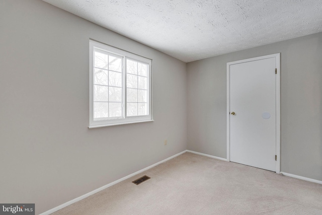 carpeted empty room featuring a textured ceiling