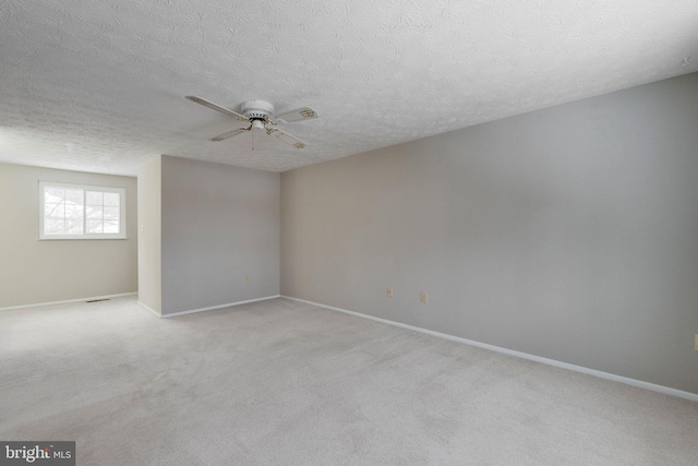 spare room featuring ceiling fan, light colored carpet, and a textured ceiling