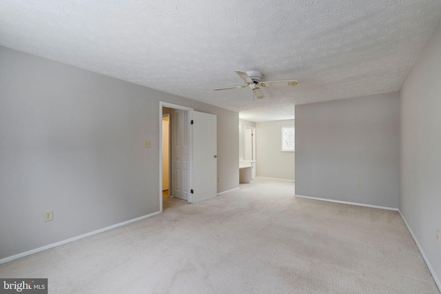 spare room featuring ceiling fan, light colored carpet, and a textured ceiling