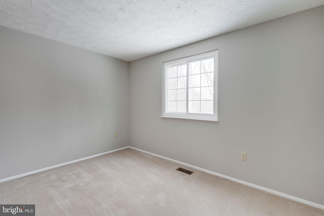 carpeted empty room featuring a textured ceiling