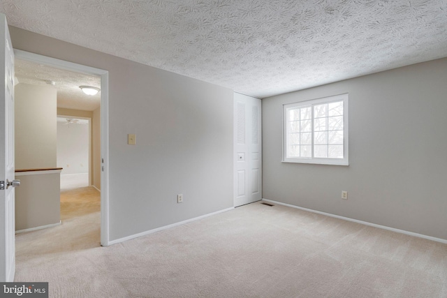 spare room with light carpet, ceiling fan, and a textured ceiling