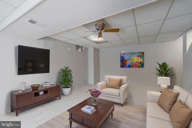 living room with ceiling fan, light wood-type flooring, and a drop ceiling