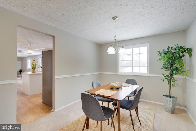 dining area featuring a chandelier, light carpet, and a textured ceiling