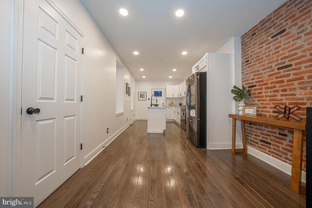 hallway featuring dark hardwood / wood-style flooring and brick wall