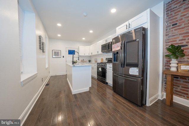 kitchen with white cabinets, stainless steel fridge, an island with sink, gas stove, and dark hardwood / wood-style flooring