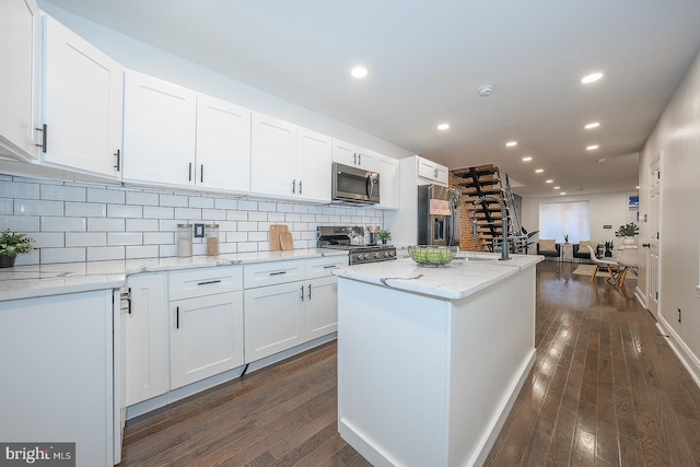 kitchen featuring light stone countertops, white cabinets, stainless steel appliances, and dark hardwood / wood-style floors