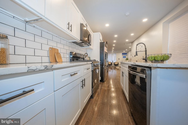 kitchen with backsplash, white cabinetry, dark wood-type flooring, and appliances with stainless steel finishes