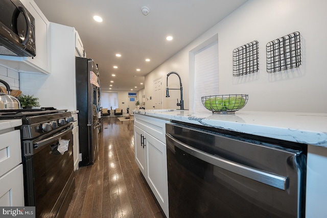 kitchen featuring dark wood-type flooring, black appliances, sink, light stone counters, and white cabinetry