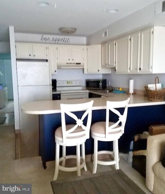 kitchen with a breakfast bar, white cabinets, kitchen peninsula, and stove