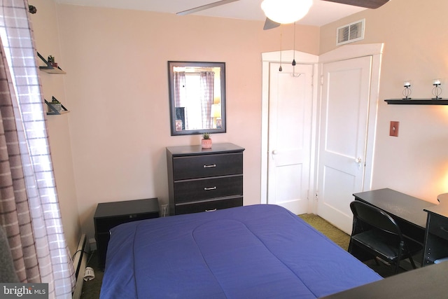 bedroom with ceiling fan, baseboard heating, and a closet