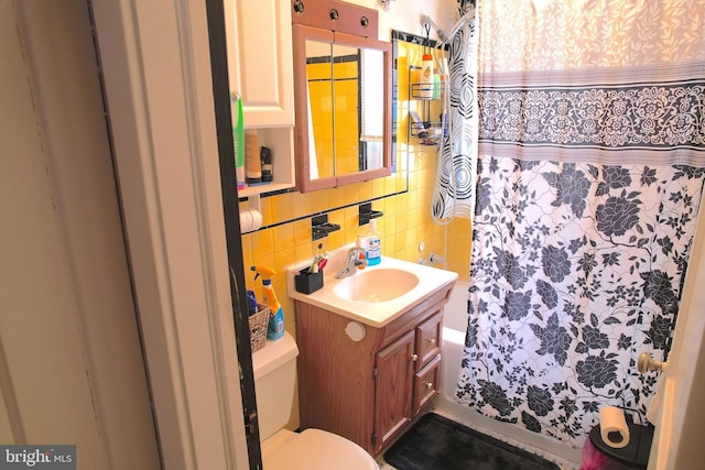 bathroom featuring walk in shower, toilet, decorative backsplash, vanity, and tile walls