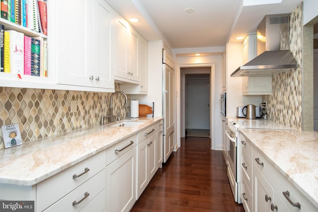 kitchen featuring range with electric cooktop, light stone counters, wall chimney exhaust hood, sink, and white cabinetry