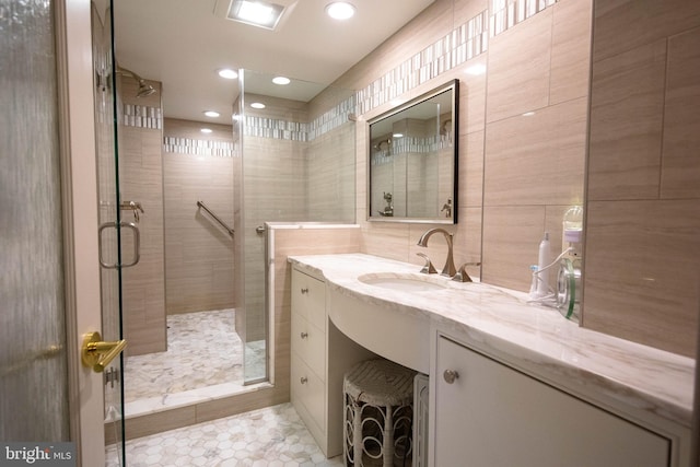 bathroom featuring tile patterned flooring, vanity, a shower with shower door, and tile walls