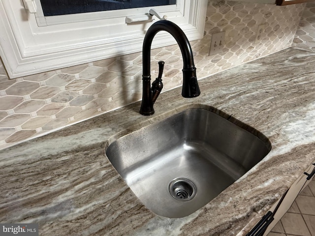 interior details with stone counters, white cabinetry, and sink